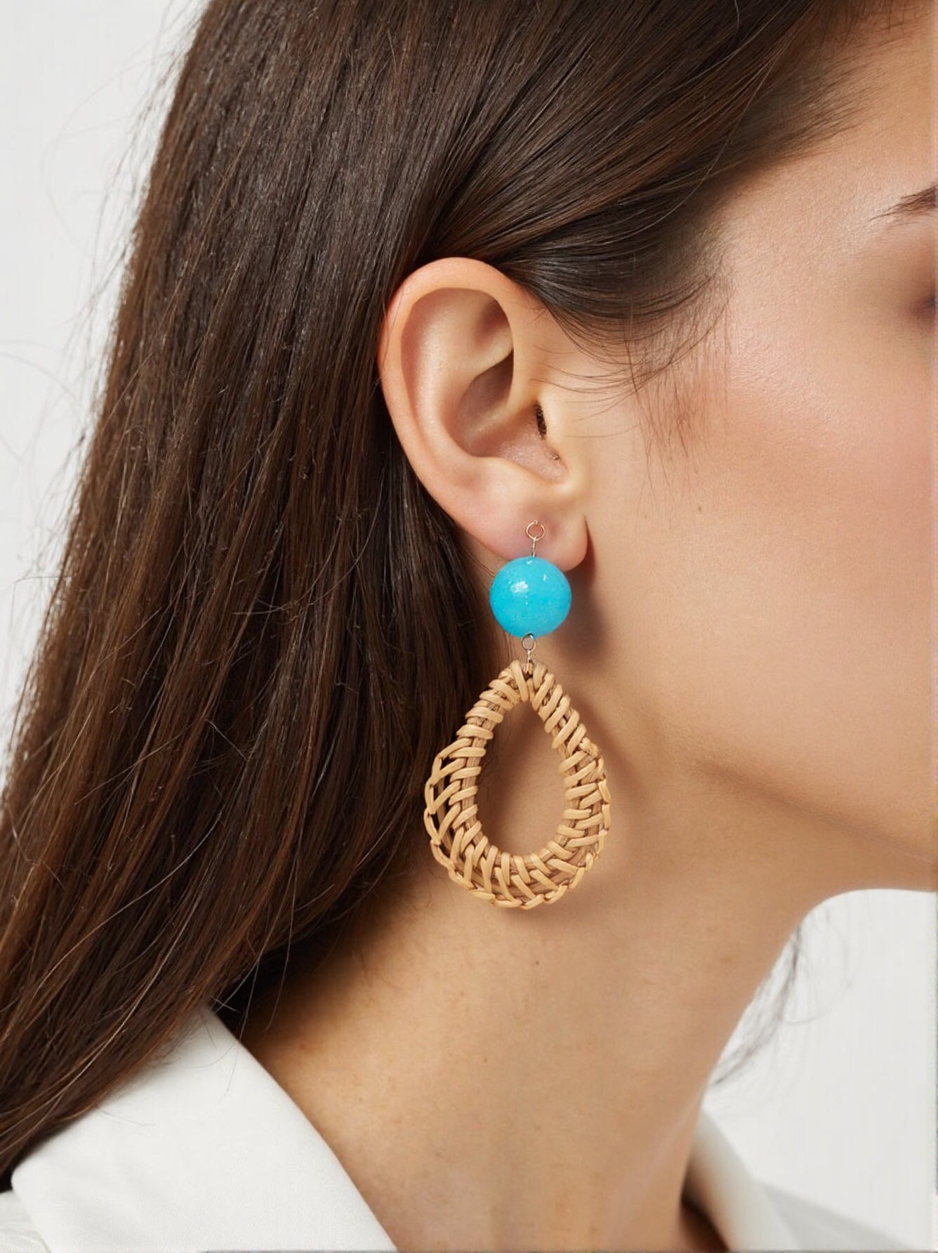 Woven teardrop earrings with turquoise resin bead on woman’s ear