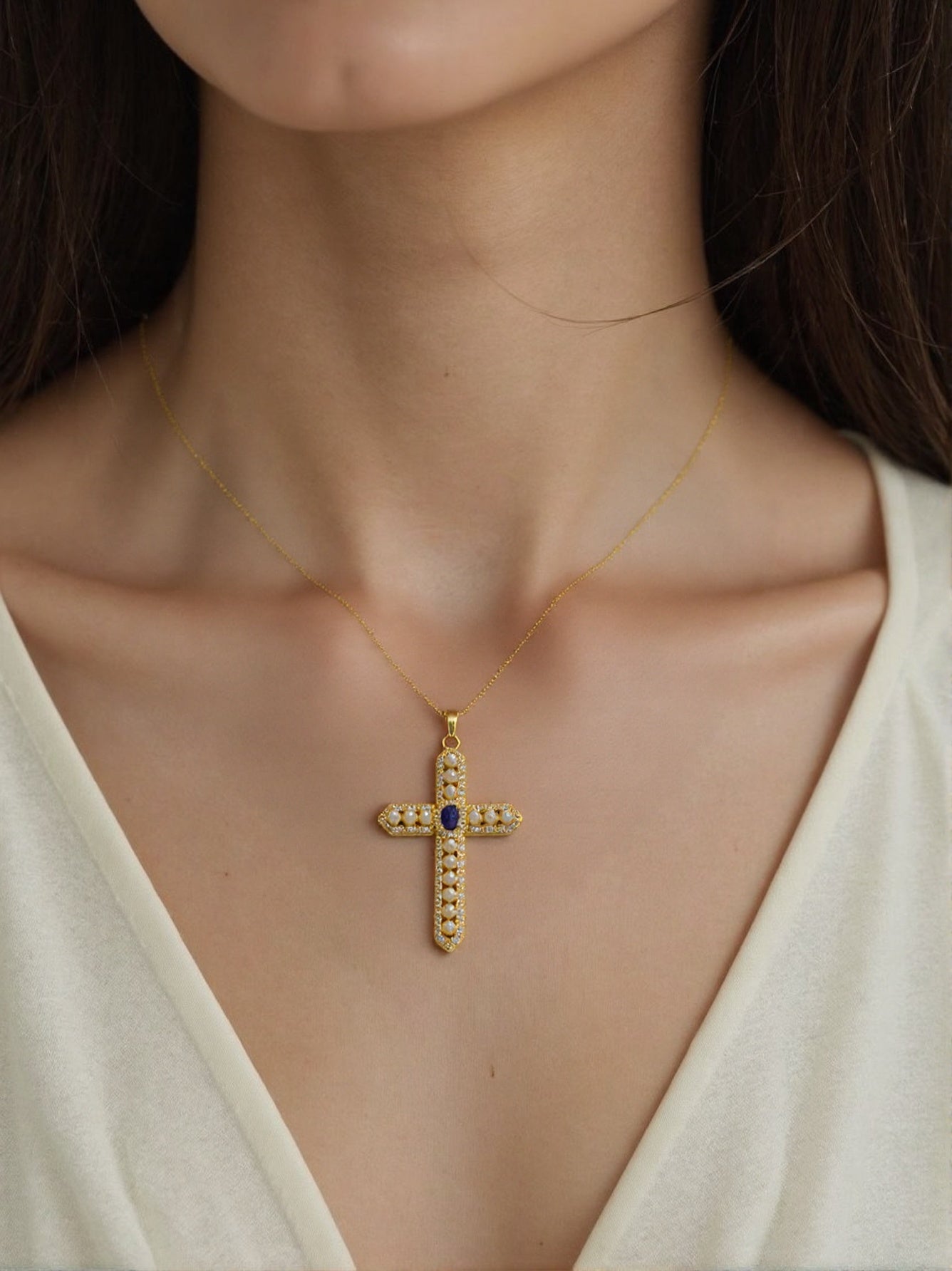 Gold necklace with pearl-studded cross pendant and blue gemstone center 